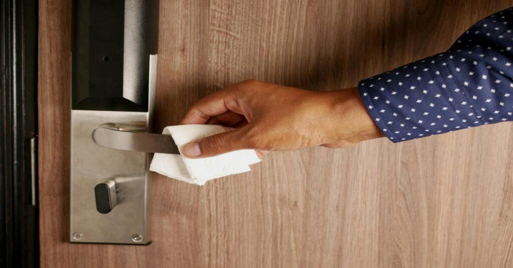 Close up hand locking hotel room door security latch from inside