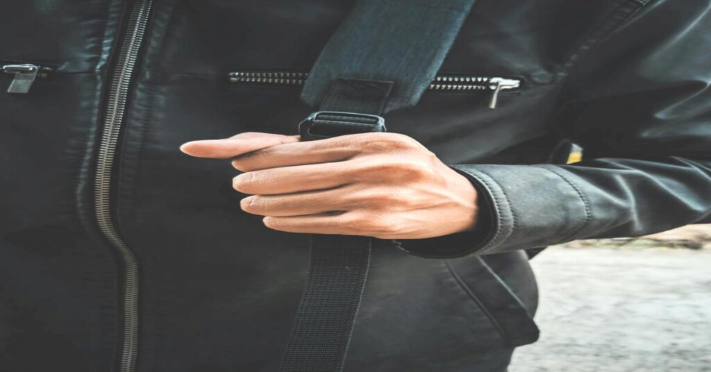 hands holding anti theft crossbody backpack close up city street