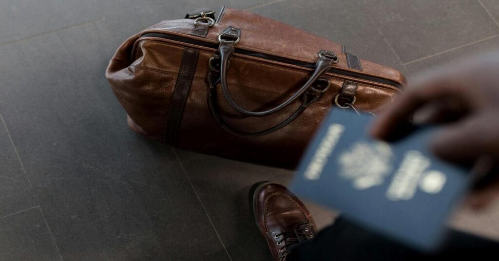 Solo travel budget tips featured image showing a minimalist backpacker holding a passport near their travel luggage