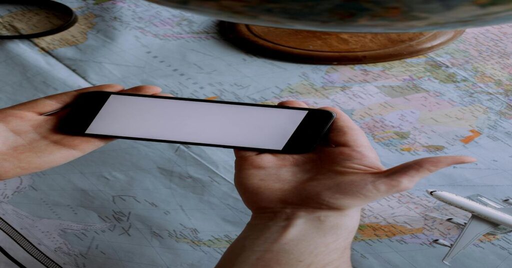 Solo Travel Tips for Women: 15 Safe Ways to Explore Alone 3 person holding smartphone looking at map hotel keys table overhead