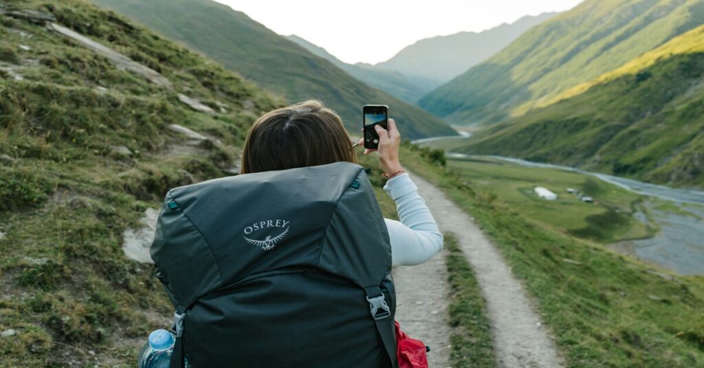Digital Minimalism for Solo Travelers: Smart Tips to Simplify – solo backpacker using one smartphone and offline map in a scenic landscape, showing minimal tech gear and fewer apps for smarter travel.