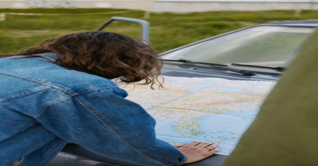 Woman sitting in car planning route with map phone calm focused