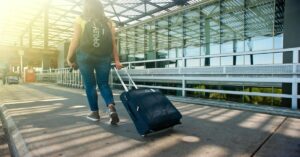 Solo Travel 3 7 Life-Changing Carry-On Backpacks for International Travel: Solo traveler walking through airport with a stylish carry-on backpack