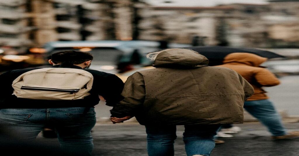 Backpackers walking together on city tour viewed from behind candid