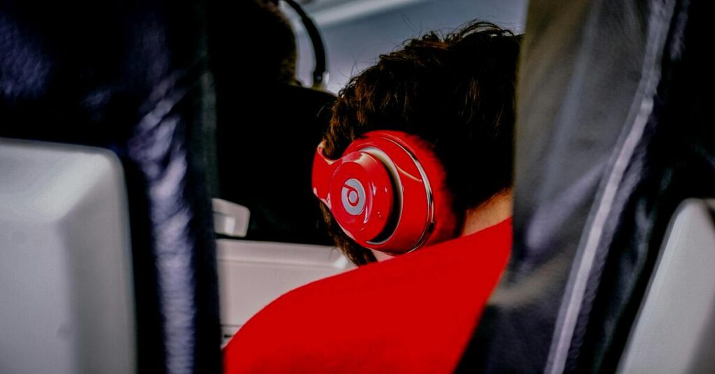 Best Noise-Canceling Headphones for Travel (2026 Flight Guide) 3 Passenger wearing large headphones inside clean commercial jet aircraft cabin
