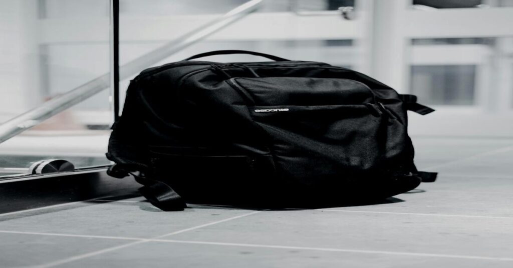 Best Travel Backpack for Organization: Top 7 Picks (2026) 3 Sleek black tech travel backpack sitting neatly on airport terminal seating