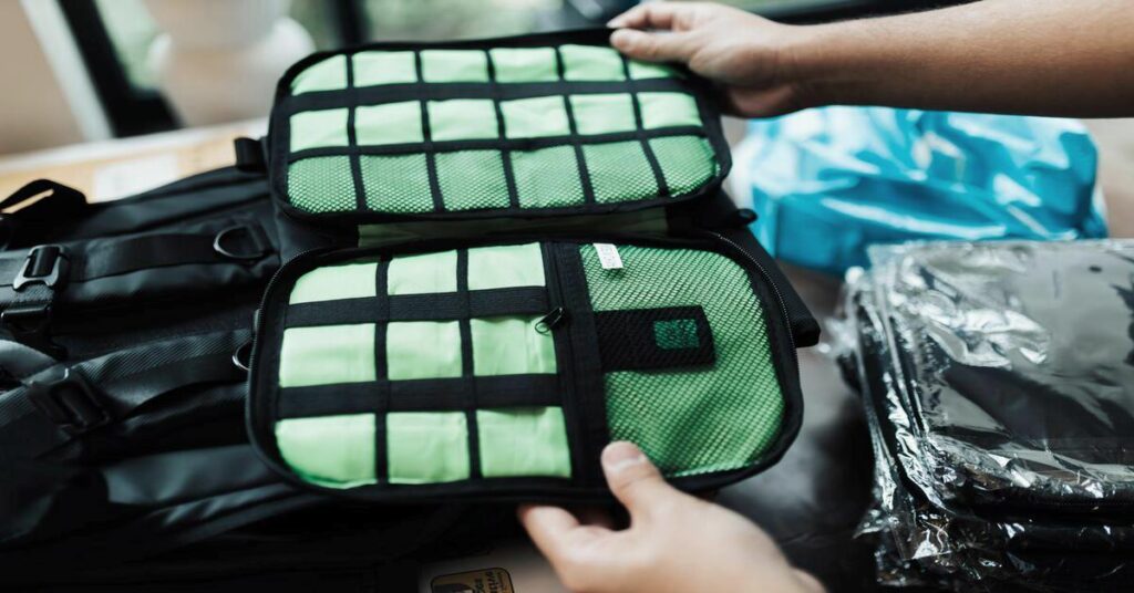 Minimalist travel backpack open flat on bed showcasing neat interior organizing pockets
