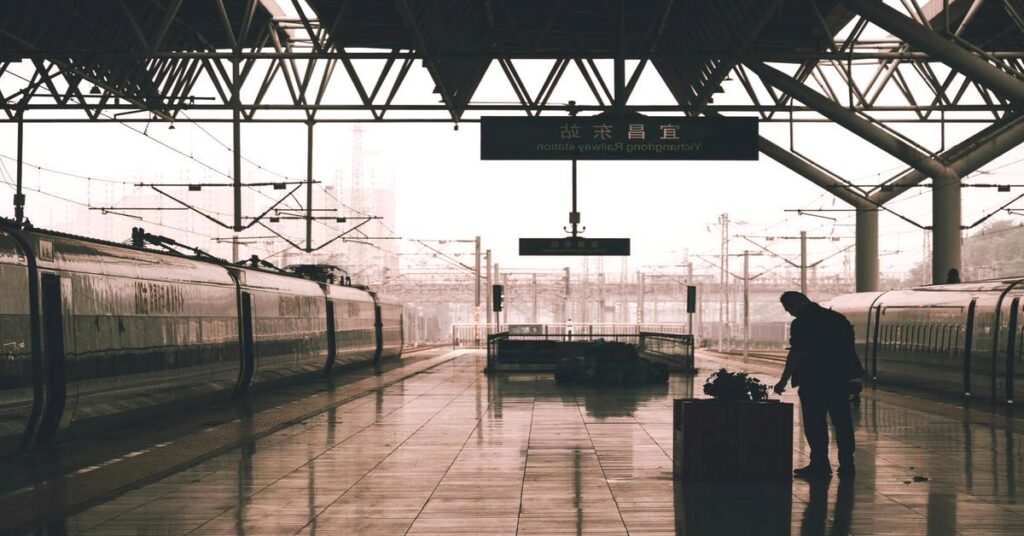 solo traveler silhouette standing on a train platform waiting looking forward