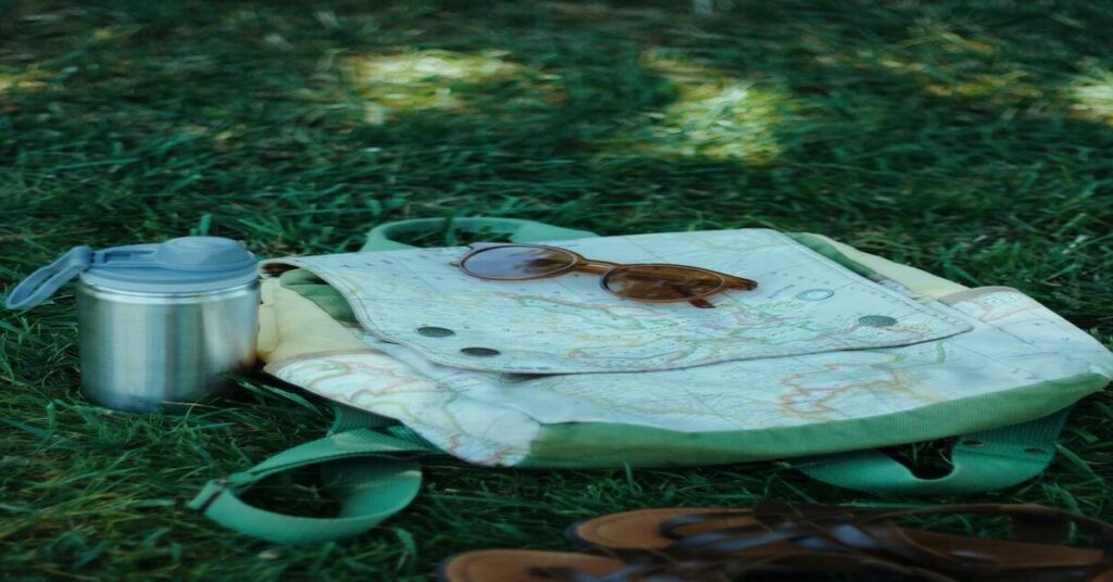 Collapsible electric tea kettle folded completely flat next to a backpack clean layout passport view