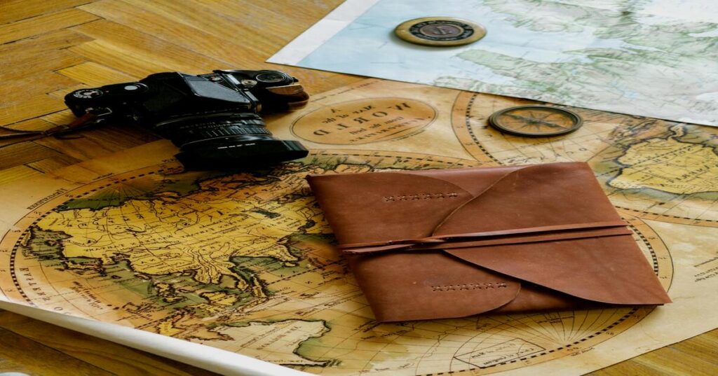 Premium brown leather vintage pocket journal open beside printed paper roadmap on old wooden table